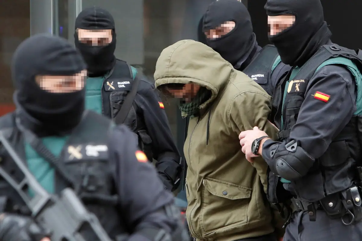 Agentes de la Guardia Civil con pasamontañas escoltan a un detenido con capucha y rostro pixelado durante un operativo policial Agentes de la Guardia Civil con pasamontañas escoltan a un detenido con capucha y rostro pixelado durante un operativo policial