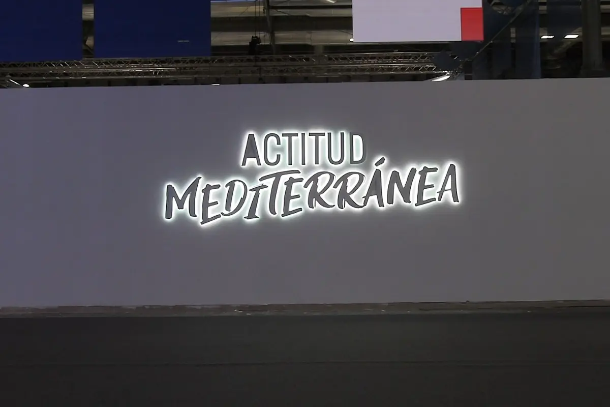 Pared gris con el letrero luminoso en español que dice ACTITUD MEDITERRÁNEA en letras blancas destacadas