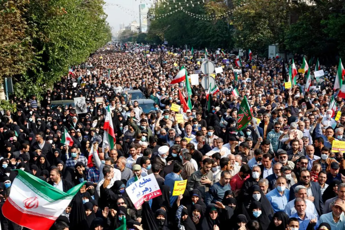 Multitudinaria manifestación en una avenida con personas portando banderas de Irán y pancartas