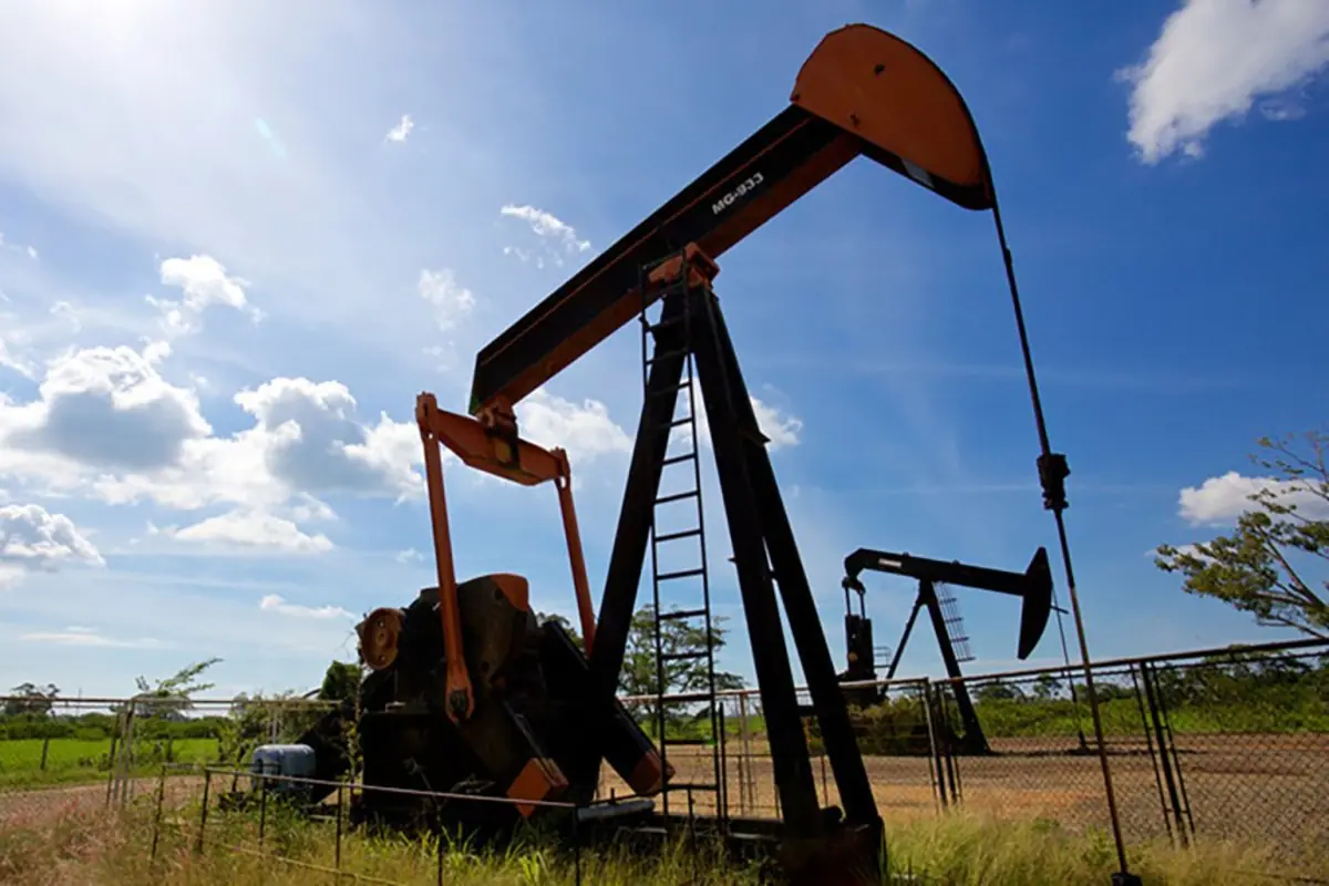 Bomba extractora de petróleo en un campo al aire libre bajo un cielo azul con nubes