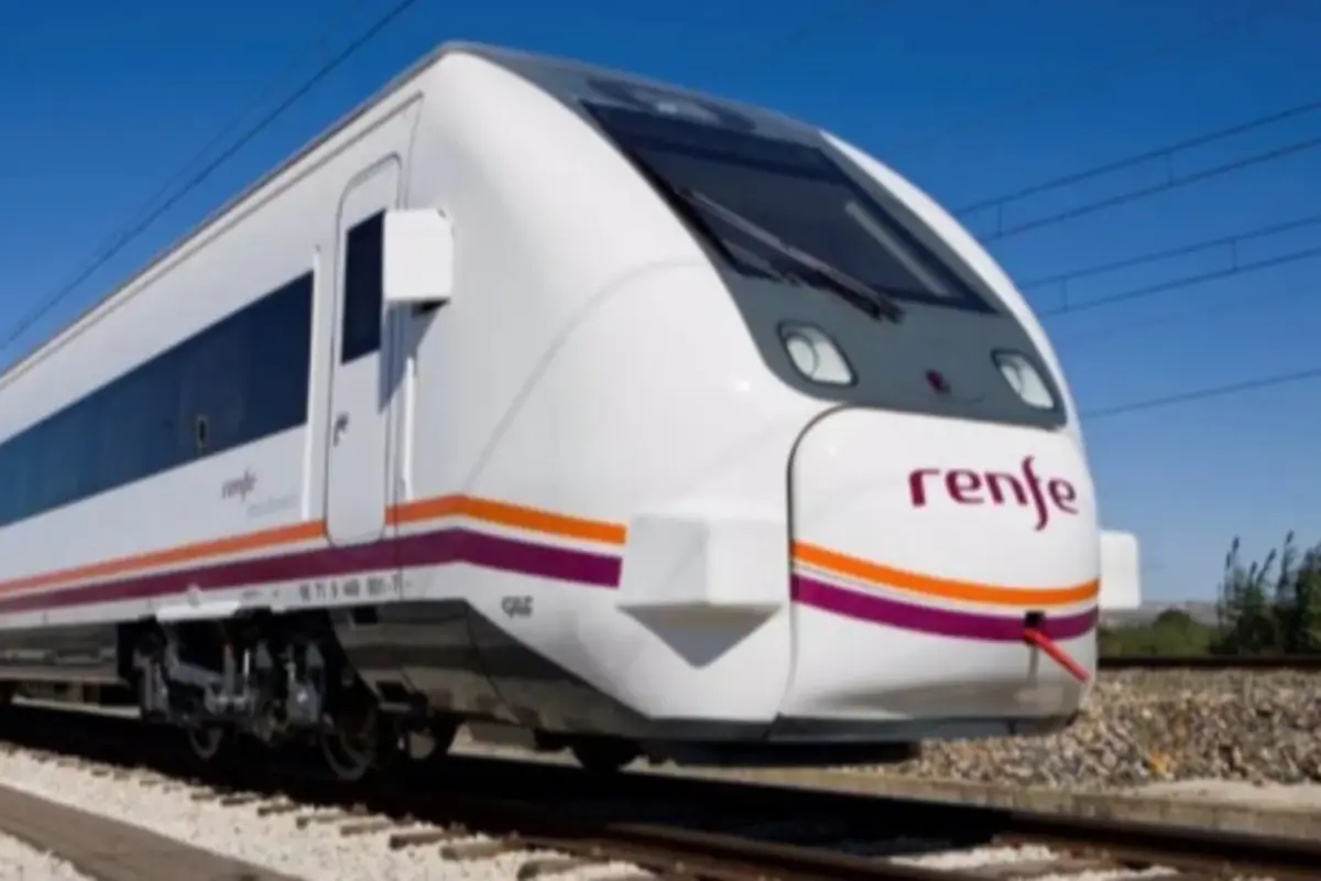 Tren moderno de la compañía Renfe circulando por una vía férrea bajo un cielo despejado