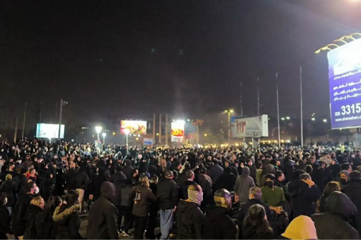 Multitud de personas reunidas de noche en una gran manifestación al aire libre con carteles y anuncios luminosos al fondo Multitud de personas reunidas de noche en una gran manifestación al aire libre con carteles y anuncios luminosos al fondo