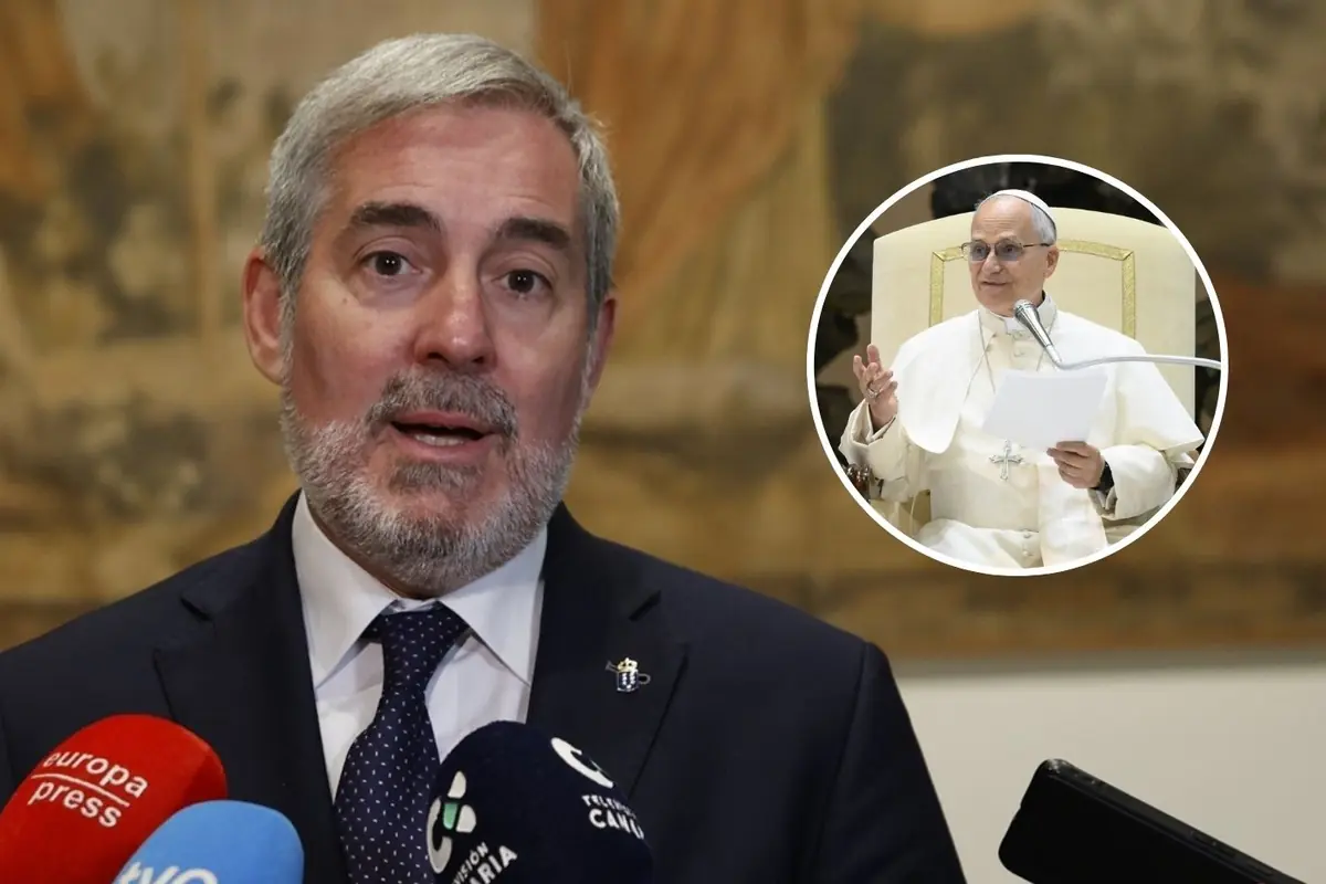 Hombre de traje hablando ante varios micrófonos en una rueda de prensa con la imagen de un líder religioso vestido de blanco en un recuadro circular al fondo