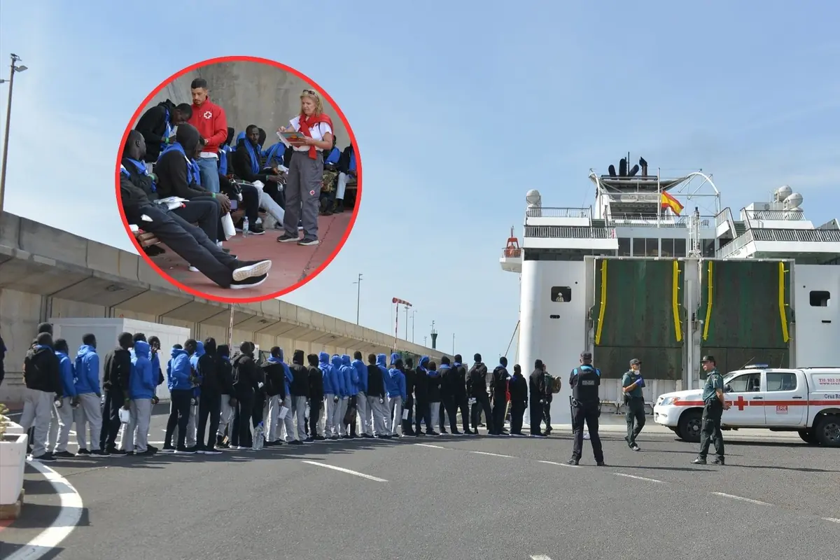 Grupo de personas migrantes con sudaderas azules y negras hace fila frente a un ferry blanco custodiado por agentes y un vehículo de la Cruz Roja mientras en un recuadro se ve a voluntarios de la Cruz Roja atendiendo y registrando a varias de estas personas sentadas en el muelle