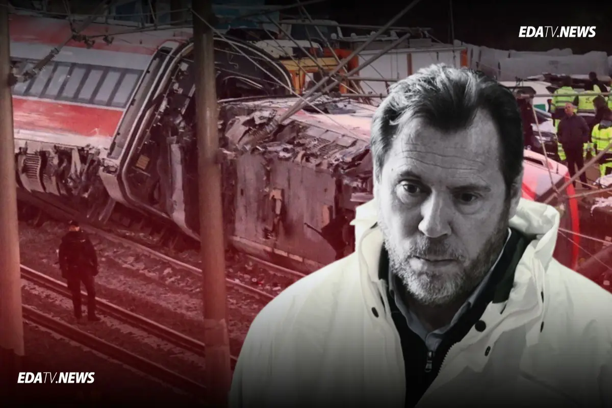 Hombre con gesto serio en primer plano frente a los restos destrozados de un tren descarrilado con personal de emergencia trabajando al fondo