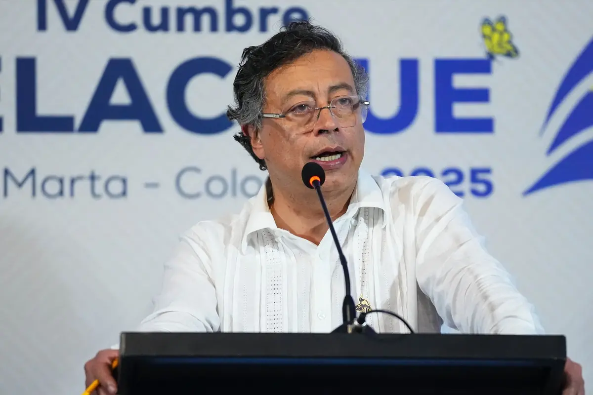 Hombre de mediana edad con gafas y camisa blanca hablando frente a un micrófono en un podio durante una cumbre en Colombia