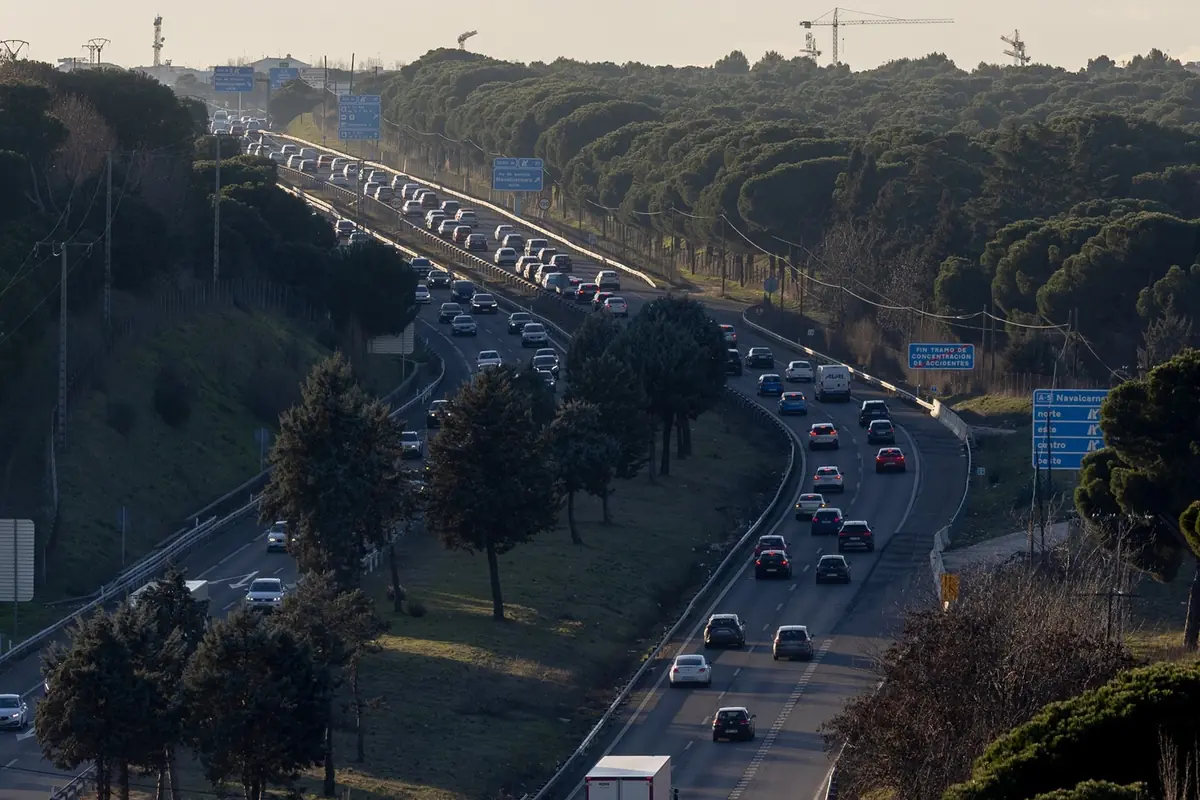 Carretera de varios carriles con tráfico denso de coches rodeada de árboles y señales azules de dirección Carretera de varios carriles con tráfico denso de coches rodeada de árboles y señales azules de dirección
