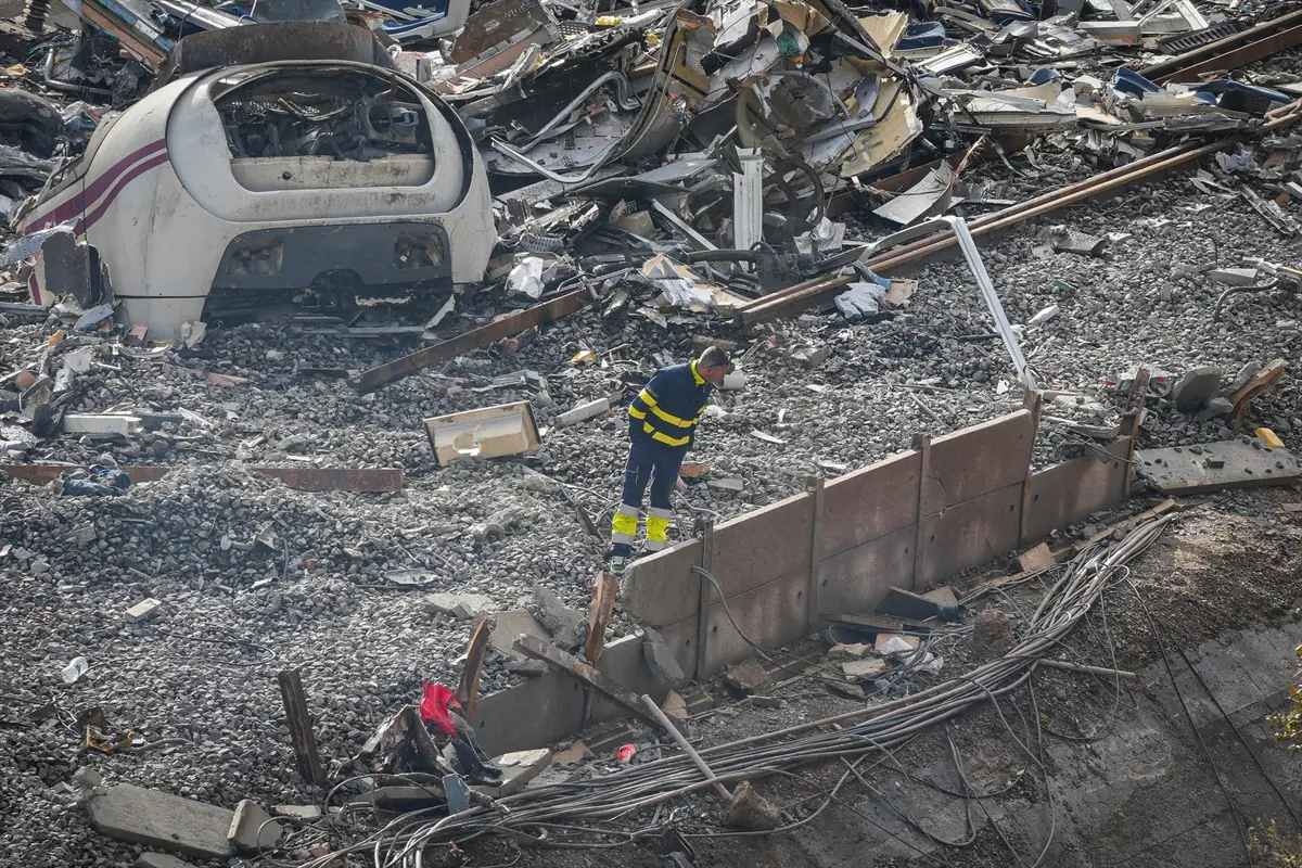 Trabajador de emergencias inspecciona entre los restos de un tren descarrilado y escombros sobre las vías