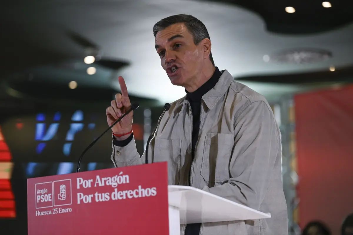Hombre hablando en un mitin político en un atril rojo con el lema Por Aragón Por tus derechos