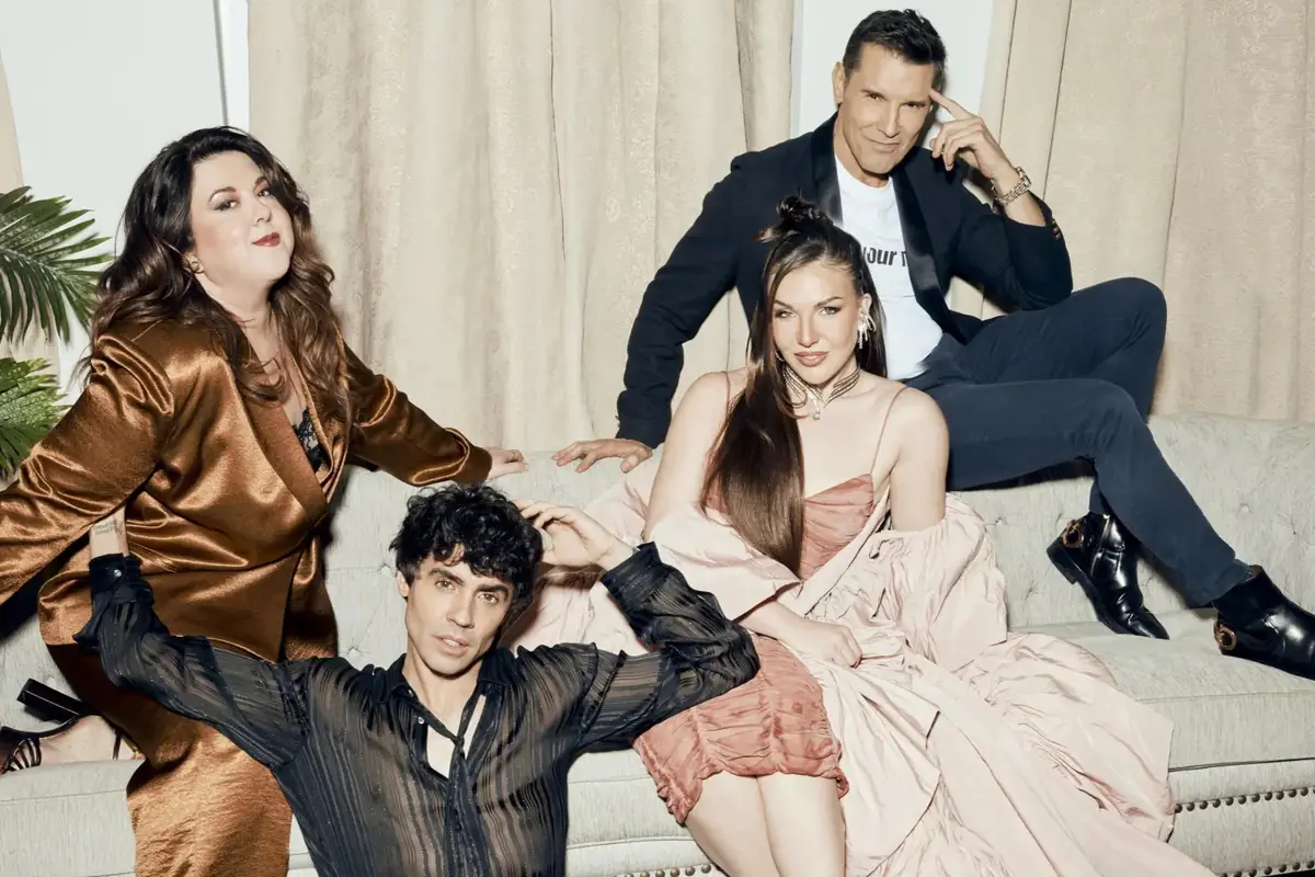 Cuatro personas posan elegantemente sobre un sofá en una sala con cortinas claras y plantas decorativas