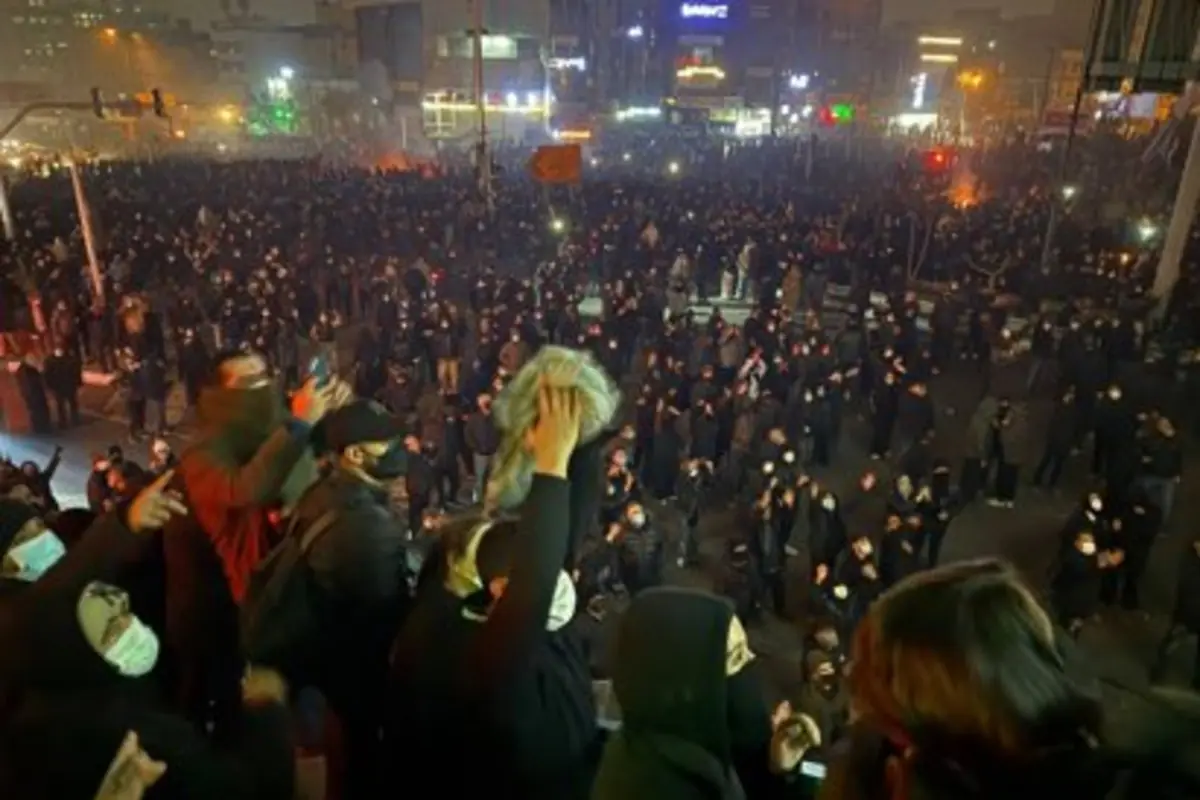 Multitud de personas con mascarillas reunidas de noche en una gran manifestación en una avenida iluminada Multitud de personas con mascarillas reunidas de noche en una gran manifestación en una avenida iluminada