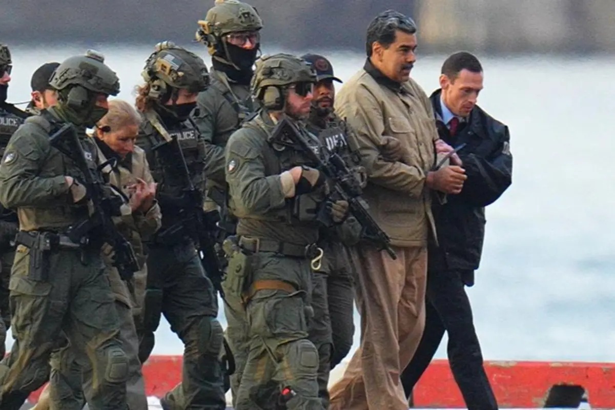 Grupo de agentes fuertemente armados escoltando a un hombre esposado junto al mar