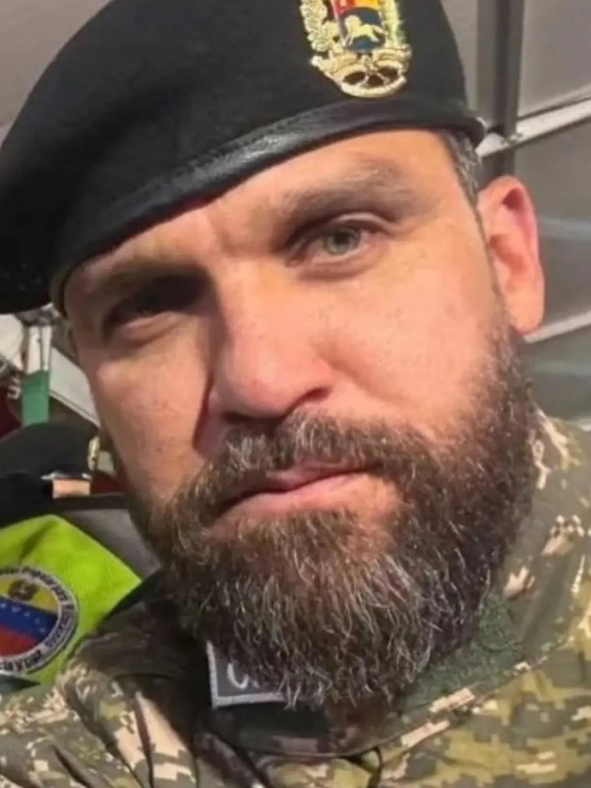 Primer plano de un militar con barba y boina negra con insignia dorada vistiendo uniforme de camuflaje
