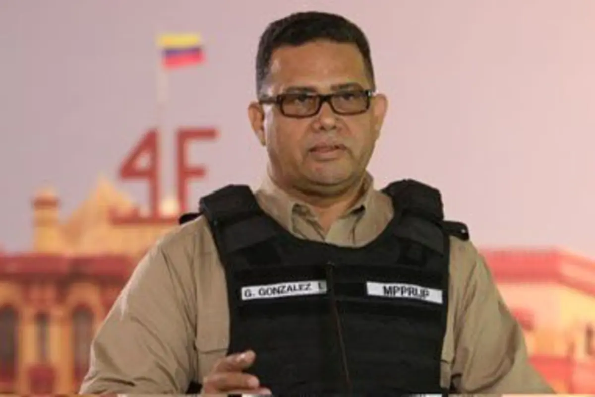 Hombre con chaleco antibalas y gafas hablando frente a un fondo con la bandera de Venezuela y las letras 4F