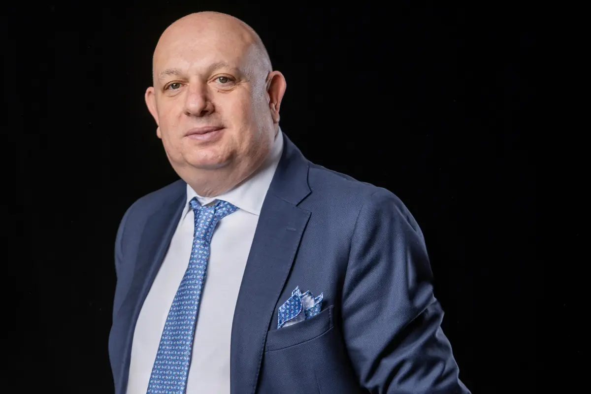 Retrato de un hombre calvo con traje azul corbata estampada y pañuelo en el bolsillo sobre fondo negro