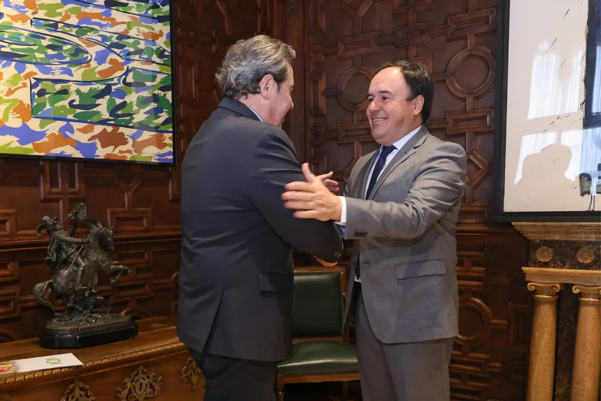 Dos hombres con traje se saludan cordialmente en una sala elegante con paredes de madera tallada y cuadros de arte moderno Dos hombres con traje se saludan cordialmente en una sala elegante con paredes de madera tallada y cuadros de arte moderno