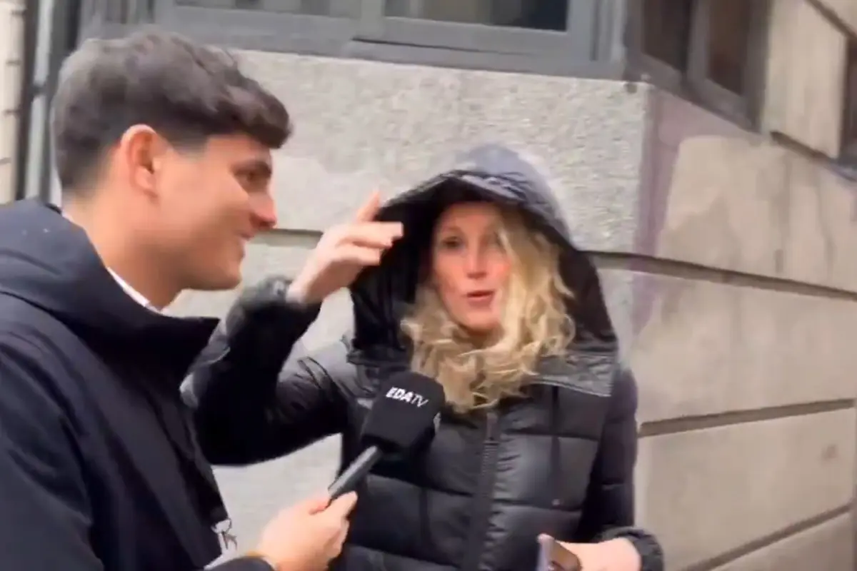 Reportero entrevistando en la calle a una mujer con abrigo y capucha levantada mientras sostiene un micrófono de EDA TV Reportero entrevistando en la calle a una mujer con abrigo y capucha levantada mientras sostiene un micrófono de EDA TV
