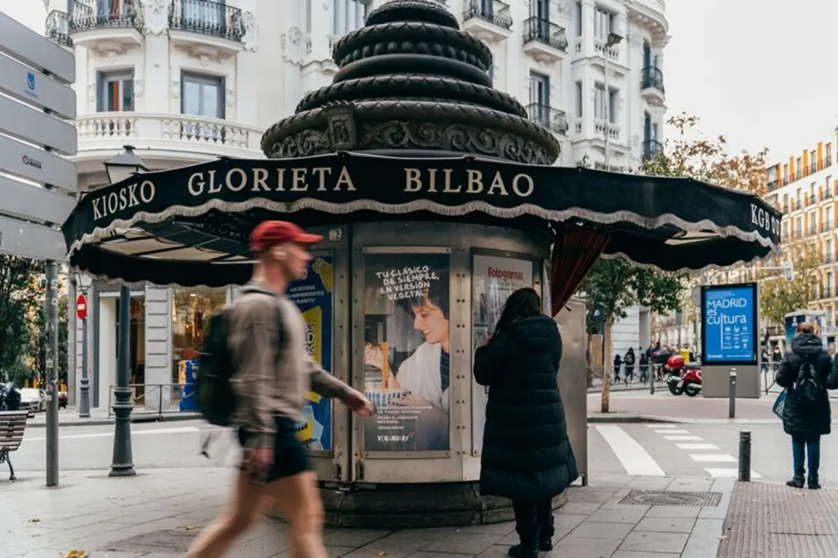 Kiosco circular en la Glorieta de Bilbao en una calle urbana con personas caminando y edificios residenciales al fondo
