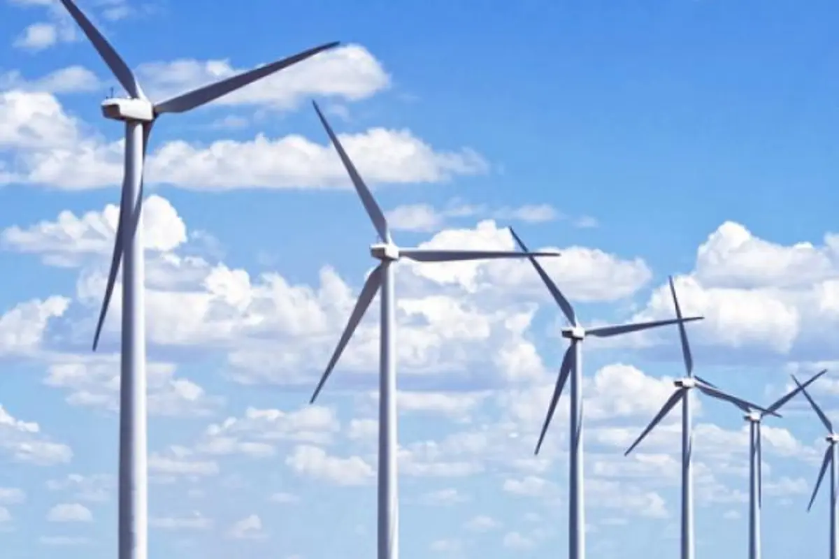 Fila de aerogeneradores en un parque eólico bajo un cielo azul con nubes Fila de aerogeneradores en un parque eólico bajo un cielo azul con nubes