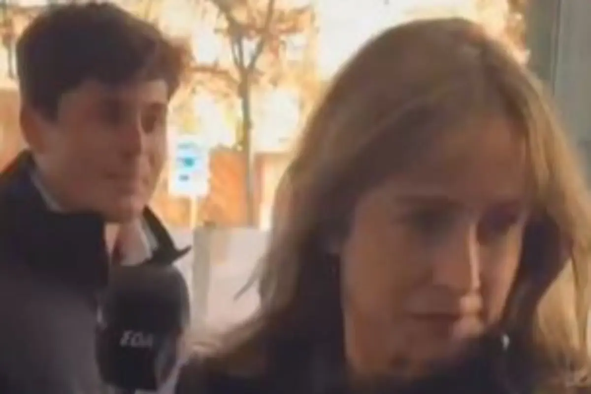 Mujer seria caminando mientras un reportero con micrófono intenta entrevistarla en la calle