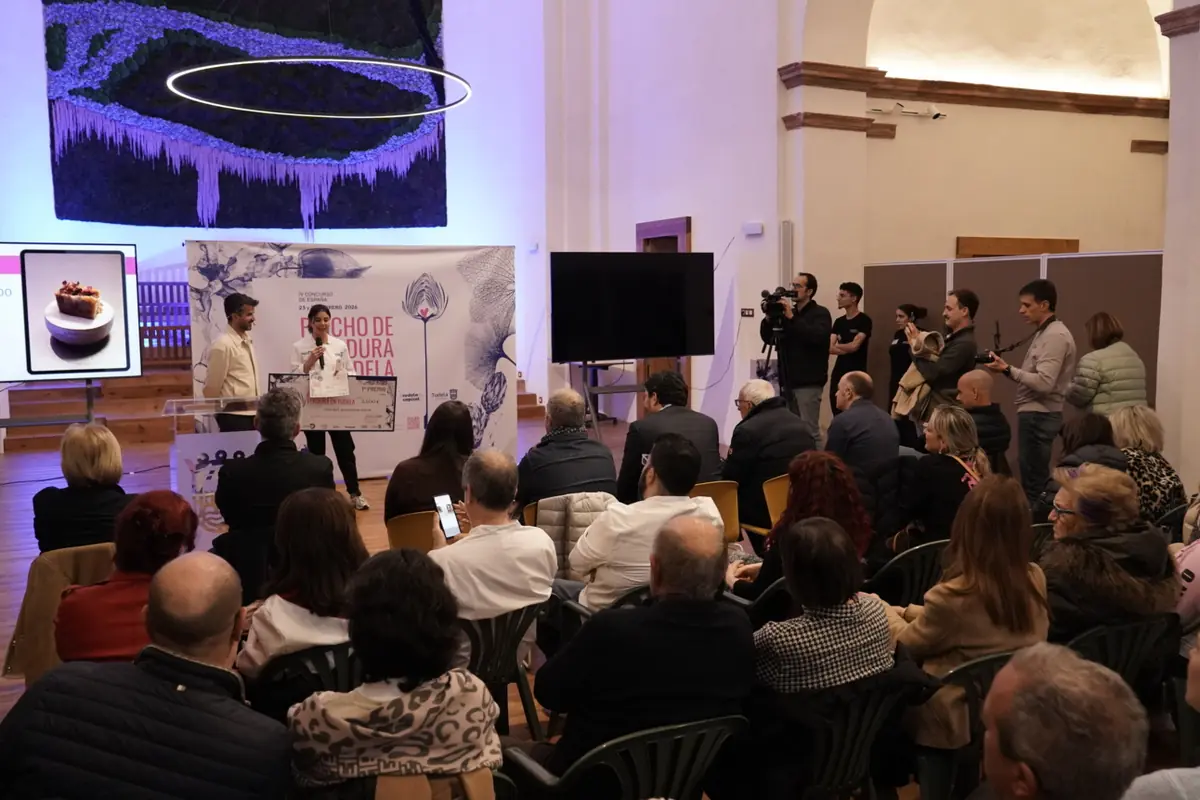 Presentación de un concurso gastronómico en un auditorio con dos ponentes en el escenario frente a un público sentado mientras se proyecta la imagen de un postre en una pantalla Presentación de un concurso gastronómico en un auditorio con dos ponentes en el escenario frente a un público sentado mientras se proyecta la imagen de un postre en una pantalla