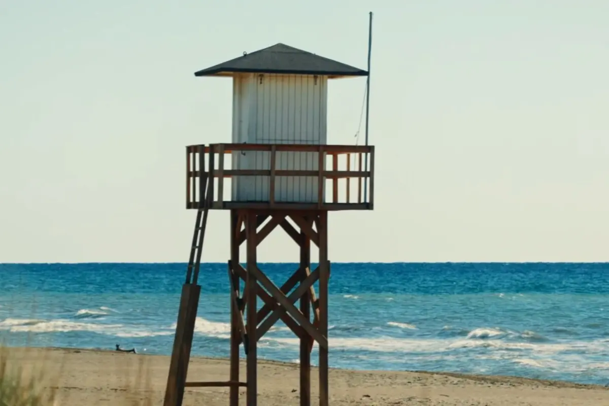 Torre de vigilancia de madera en una playa frente al mar con olas suaves