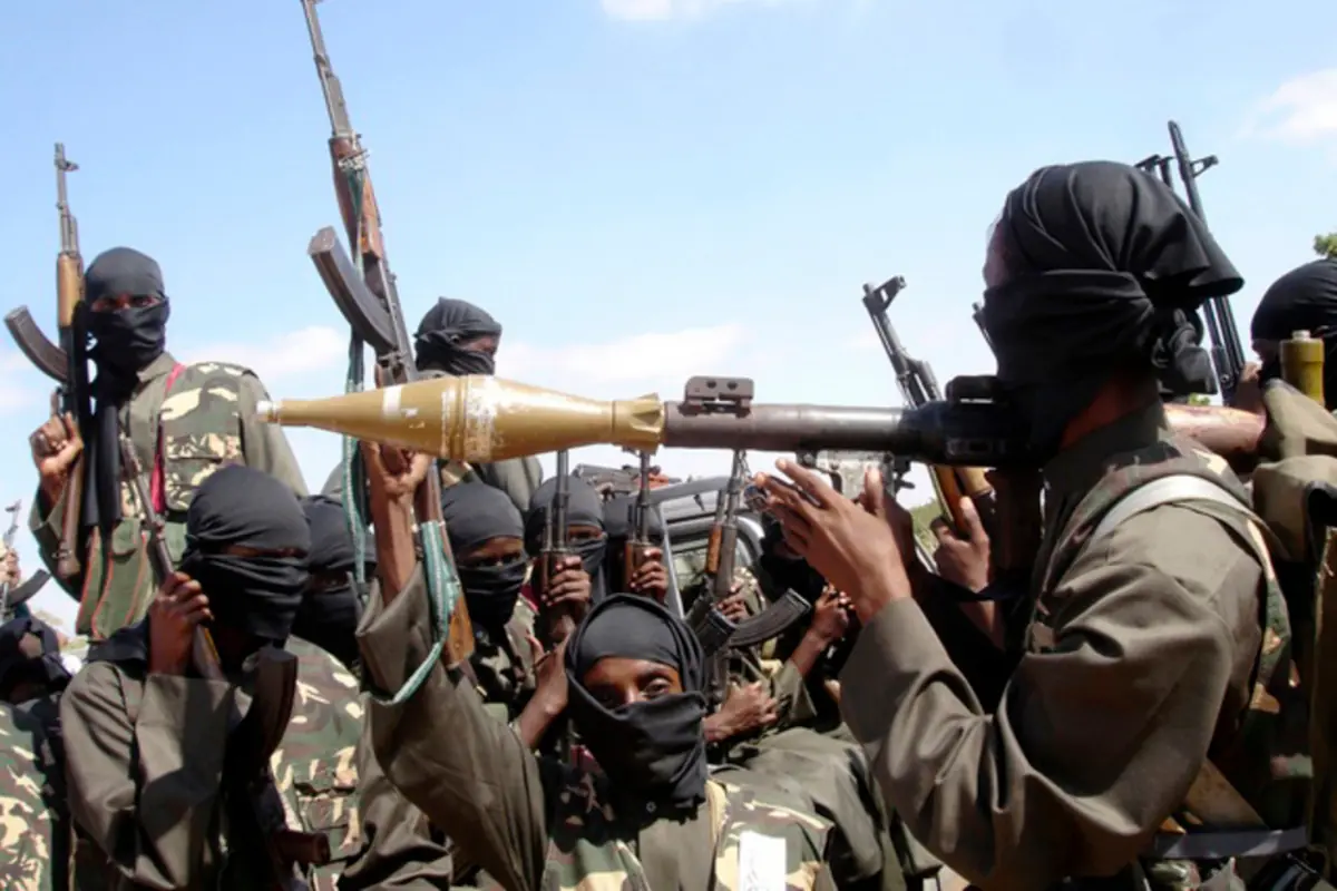 Grupo de hombres encapuchados con ropa de camuflaje sosteniendo rifles y un lanzacohetes en actitud de combate