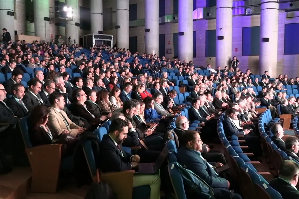 Auditorio lleno de personas sentadas en butacas azules asistiendo a una conferencia o evento profesional