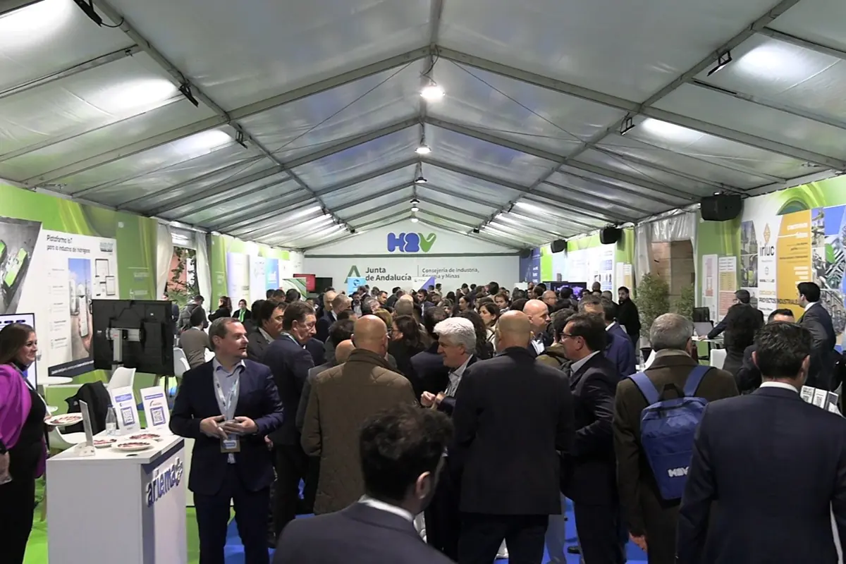 Gran carpa expositiva llena de personas de negocios conversando y visitando stands informativos de la Junta de Andalucía y otras entidades