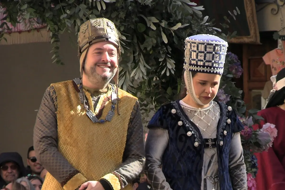 Pareja vestida con trajes medievales ornamentados participando en un desfile festivo al aire libre Pareja vestida con trajes medievales ornamentados participando en un desfile festivo al aire libre