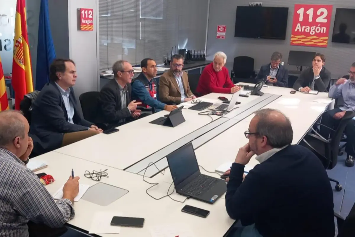 Reunión de trabajo en una sala del servicio de emergencias 112 Aragón con varias personas sentadas alrededor de una mesa grande usando portátiles y tabletas Reunión de trabajo en una sala del servicio de emergencias 112 Aragón con varias personas sentadas alrededor de una mesa grande usando portátiles y tabletas