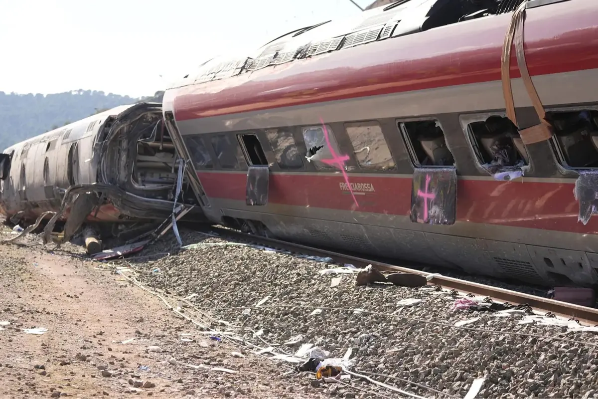 Tren de alta velocidad descarrilado y volcado sobre la vía con vagones deformados y ventanas rotas en una zona rural Tren de alta velocidad descarrilado y volcado sobre la vía con vagones deformados y ventanas rotas en una zona rural