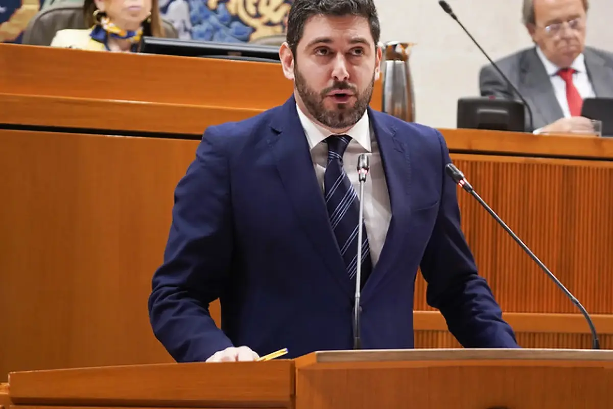 Hombre con traje azul hablando en un atril en una sala de plenos gubernamental