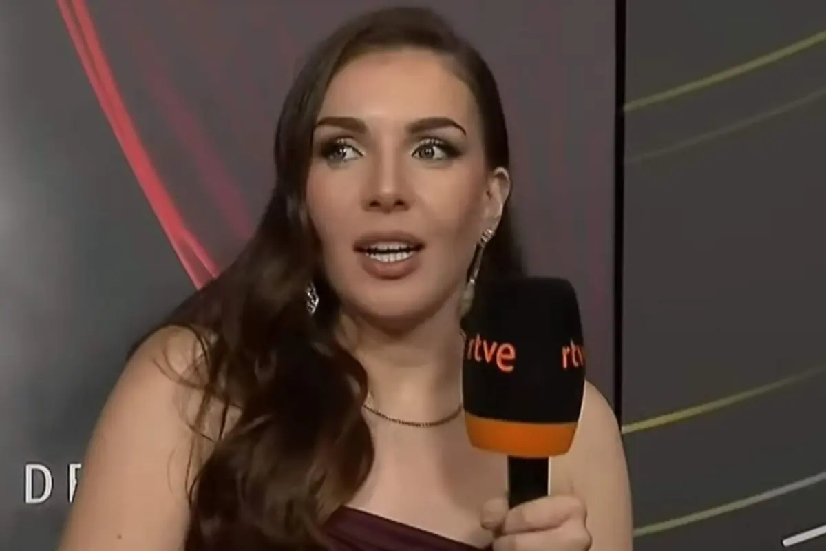 Mujer joven con vestido elegante sosteniendo un micrófono de rtve durante una entrevista en un evento