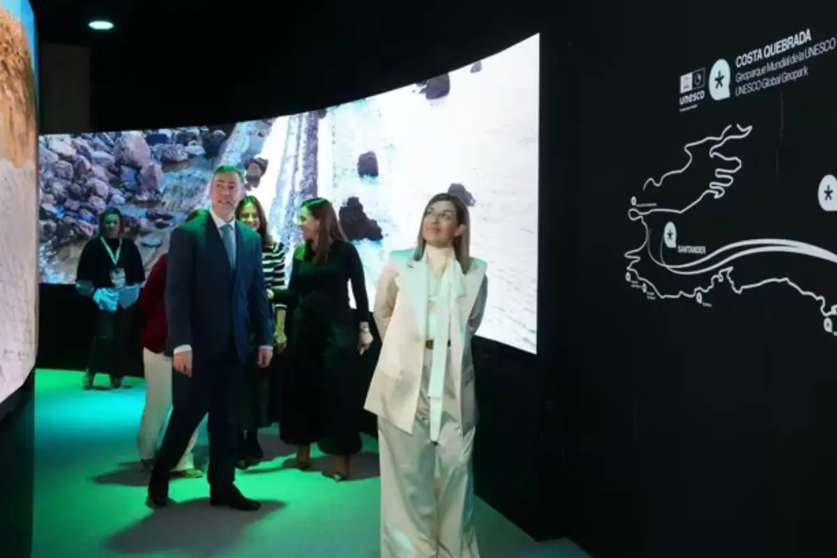 Varias personas recorren una exposición interactiva sobre la Costa Quebrada con grandes pantallas y un mapa iluminado en un espacio interior oscuro