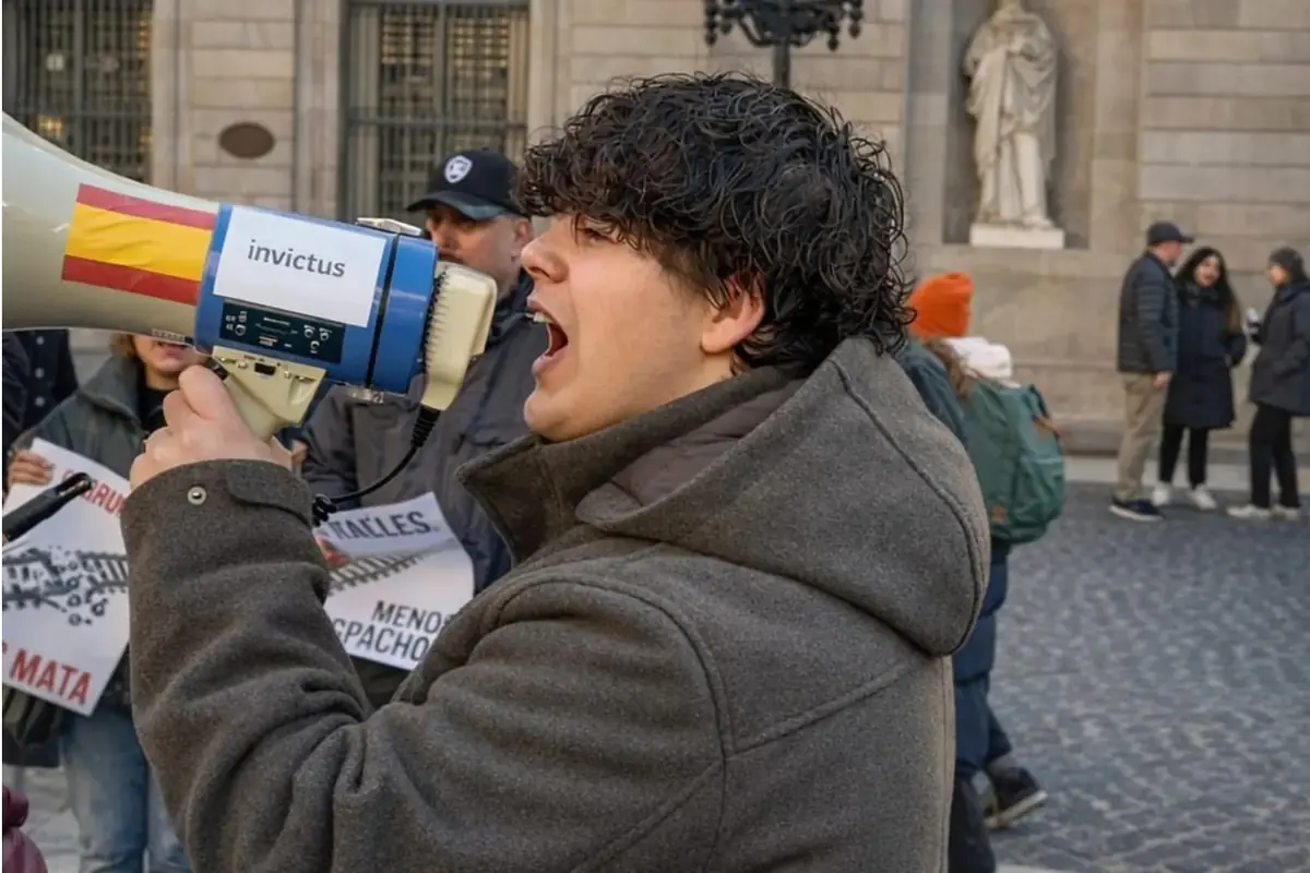 Joven con abrigo gris gritando por un megáfono durante una manifestación en la calle Joven con abrigo gris gritando por un megáfono durante una manifestación en la calle