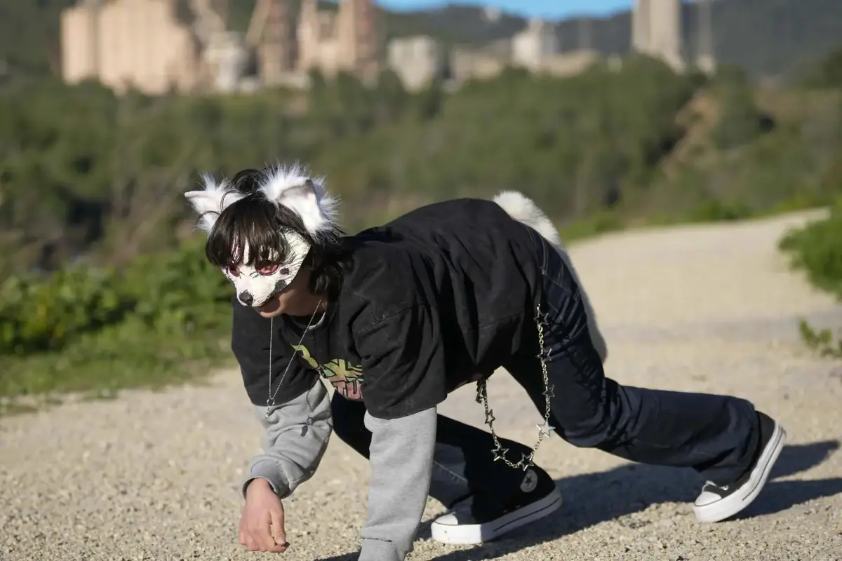 Persona con máscara y orejas de animal caminando en cuatro patas por un sendero al aire libre