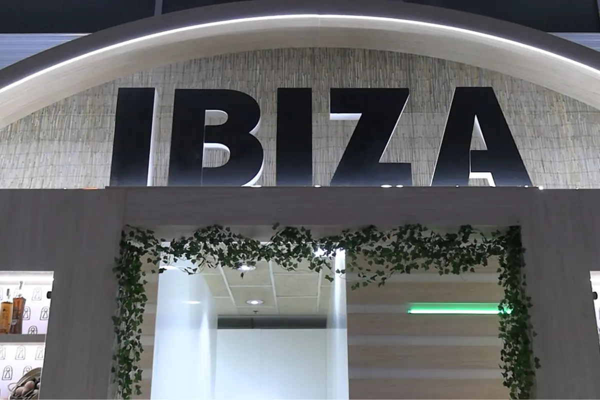 Entrada moderna con gran letrero negro que dice IBIZA sobre un arco iluminado y decorado con plantas verdes