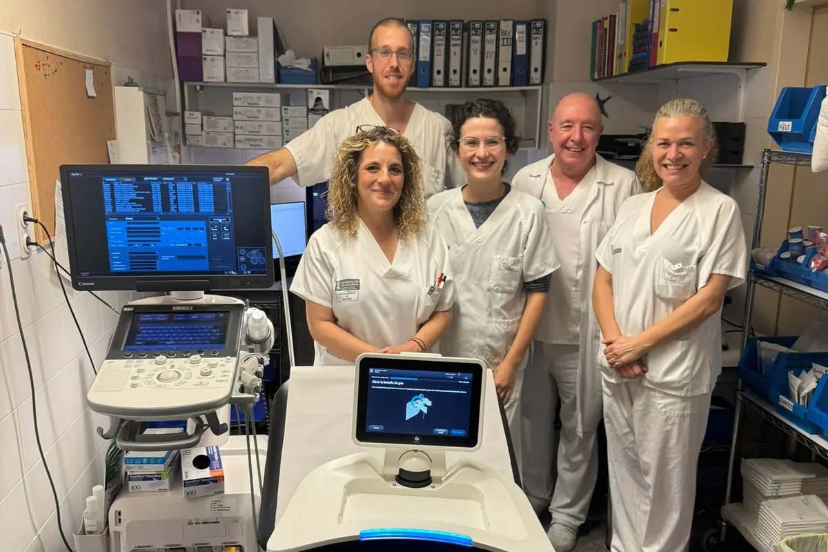 Cinco profesionales sanitarios con bata blanca posan sonrientes en una sala médica junto a equipos de ecografía y monitores clínicos