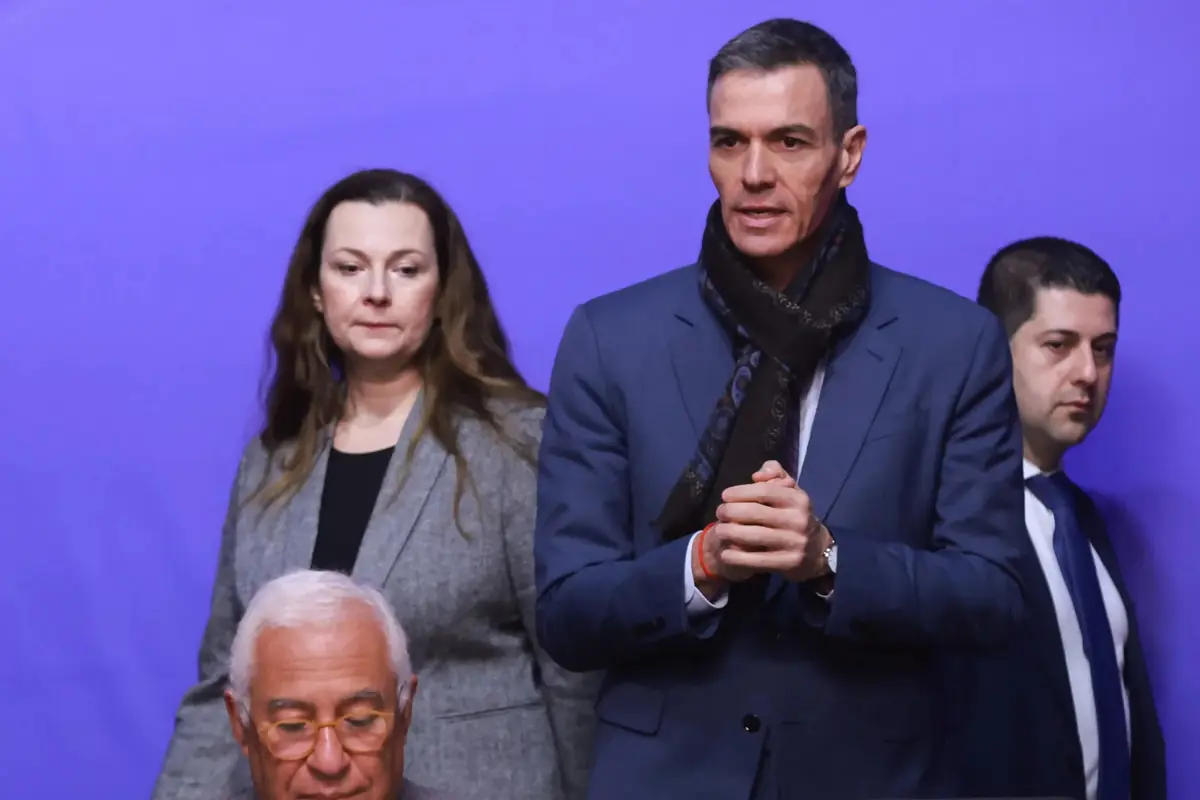 Cuatro personas con ropa formal posan frente a un fondo morado en un entorno tipo conferencia o reunión oficial
