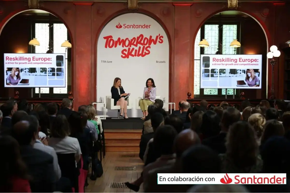 Auditorio lleno durante un evento de Santander Tomorrow’s Skills en Bruselas con dos ponentes sentadas en el escenario y pantallas que muestran el tema Reskilling Europe a driver for growth and competitiveness