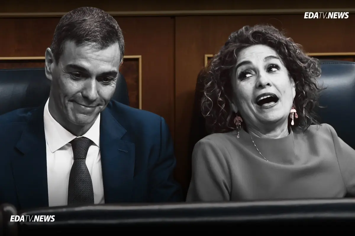 Dos personas sentadas en escaños de un parlamento una con gesto serio mirando hacia abajo y otra riendo con la boca abierta mientras conversa