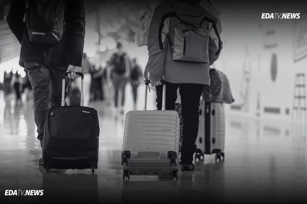Personas caminando por un pasillo de aeropuerto arrastrando maletas con ruedas