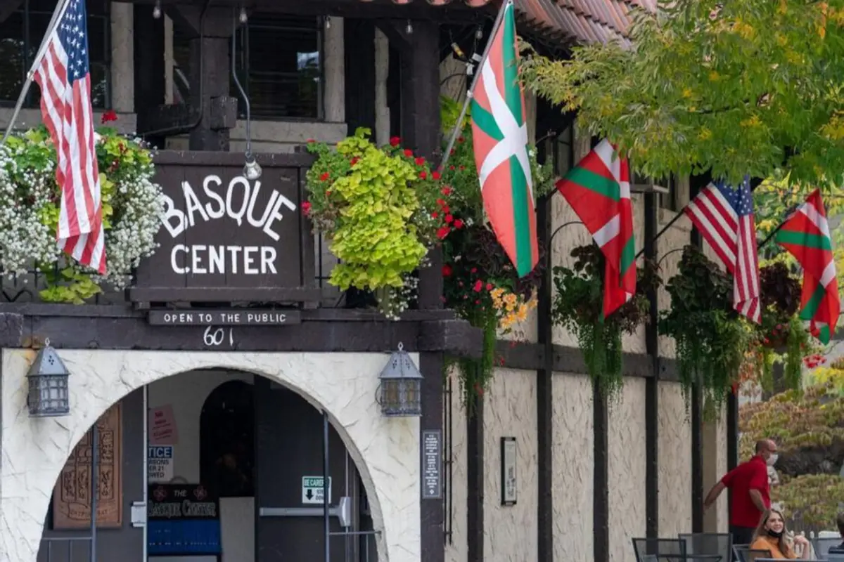 Fachada de un centro vasco con letrero Basque Center banderas de Estados Unidos y del País Vasco y macetas colgantes en la entrada