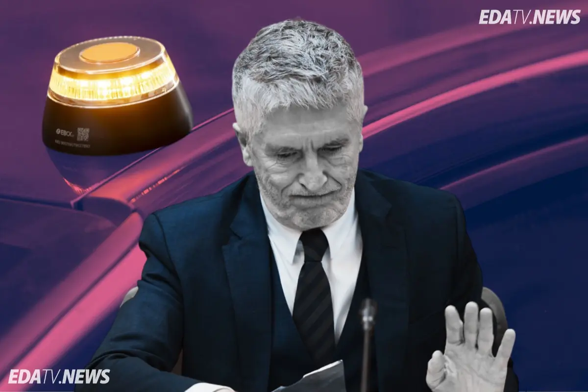 Hombre de cabello canoso con gesto serio y traje oscuro sentado ante un micrófono mientras al fondo se ve una luz de emergencia amarilla sobre un coche y el logotipo EDATV NEWS