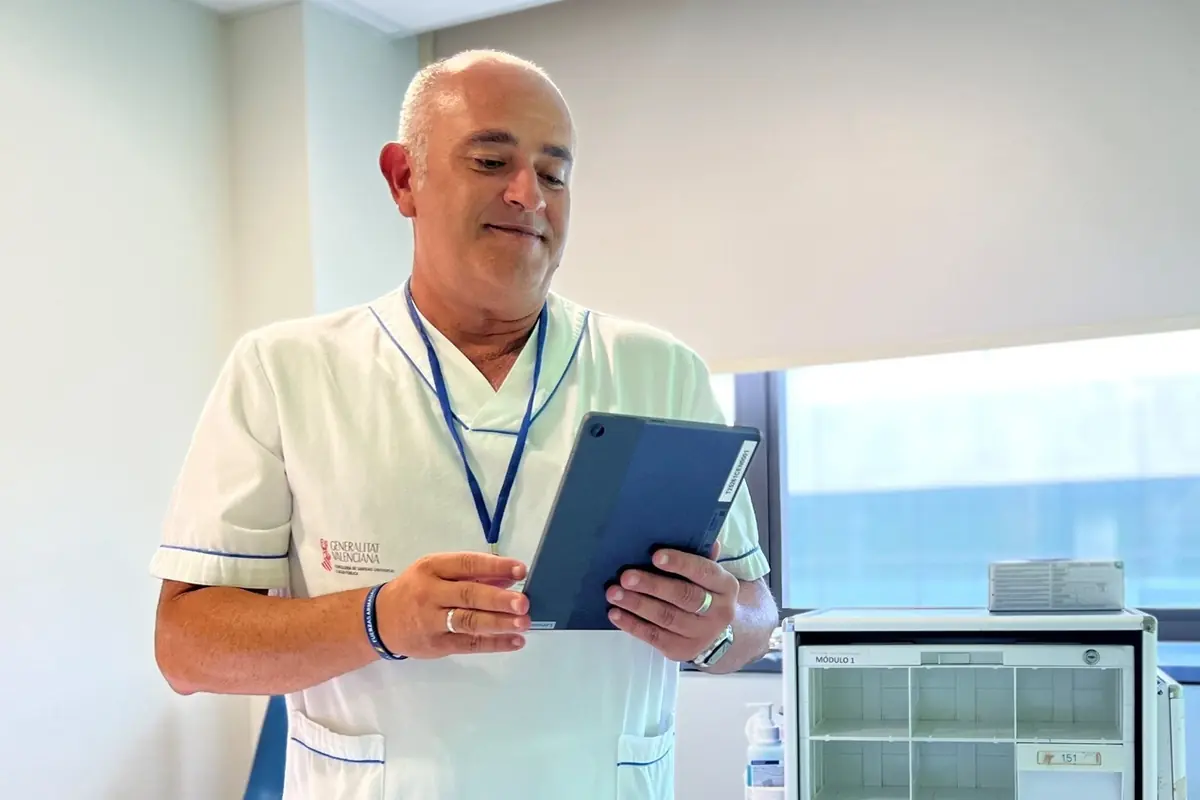 Enfermero con uniforme blanco revisando información en una tablet dentro de una sala clínica luminosa Enfermero con uniforme blanco revisando información en una tablet dentro de una sala clínica luminosa