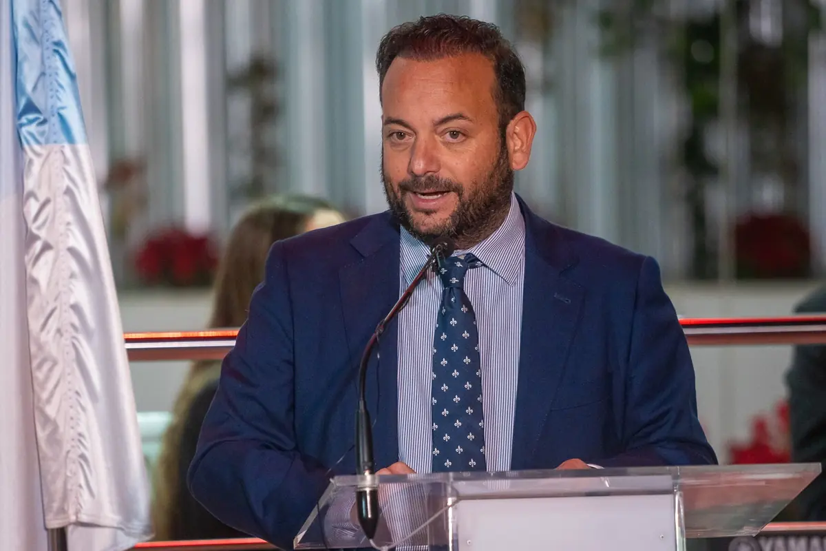 Hombre con traje azul hablando frente a un atril con micrófono en un evento formal