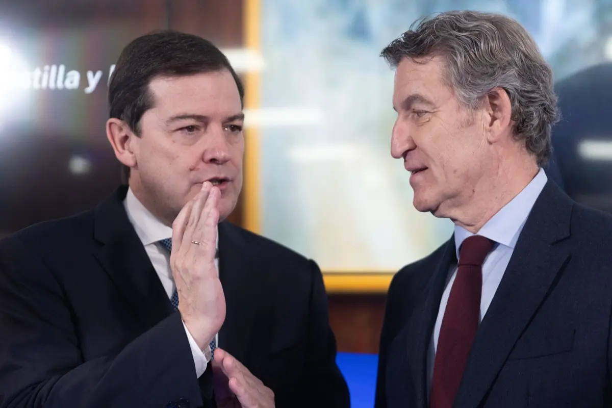 Dos hombres con traje y corbata conversan de cerca en un entorno formal