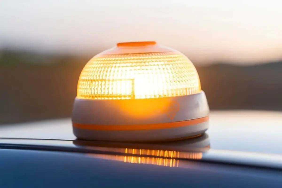 Baliza luminosa naranja encendida sobre el techo de un vehículo al atardecer Baliza luminosa naranja encendida sobre el techo de un vehículo al atardecer
