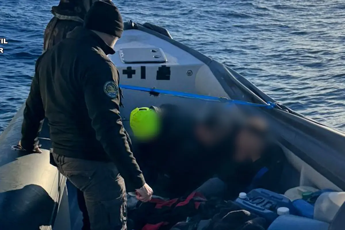 Agente de la Guardia Civil en una lancha neumática interceptando una embarcación con varias personas a bordo en alta mar